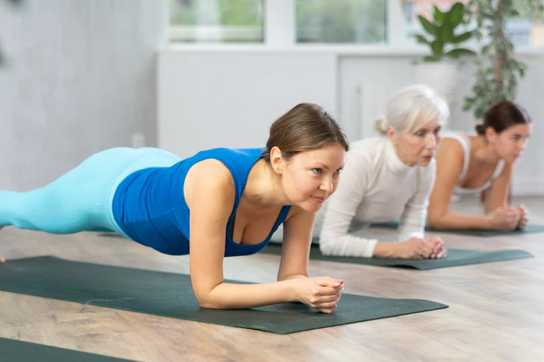 Tres mujeres realizan una plancha en un estudio de entrenamiento.