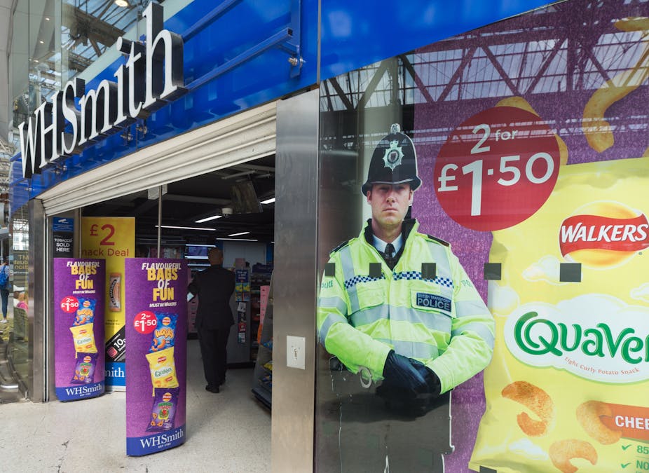 The exterior of a WH Smith shop with a cardboard cutout of a policeman in the window.