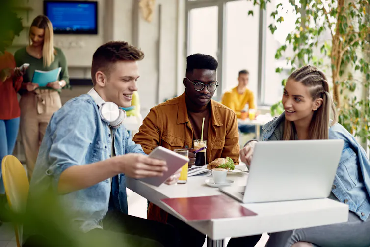 People seen sitting at a cafeteria sharing a meal.
