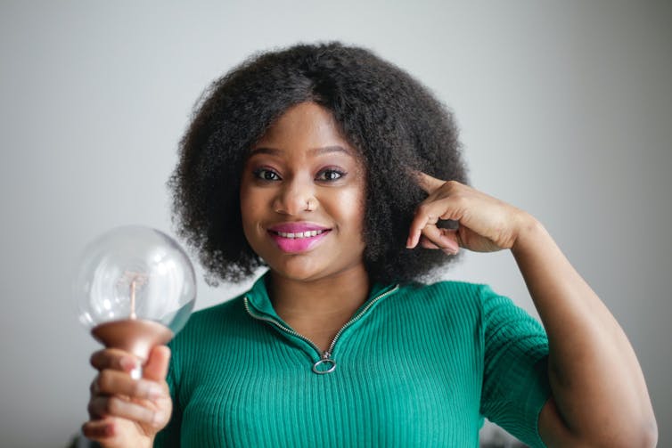 Woman showing her head and handling a light bulb
