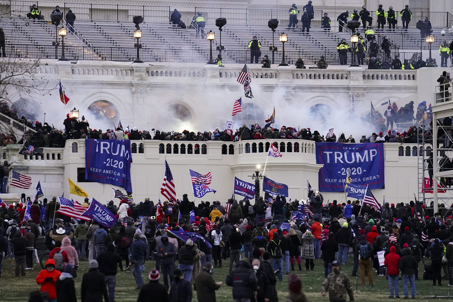 Hundreds of people storm the Capital building. Tear gas and Trump banners are seen amid the chaos.