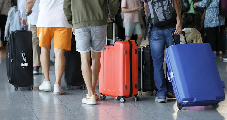 People with their suitcases in a queue at an airport