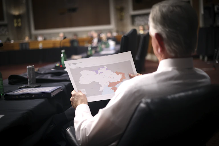 Un homme, assis, de dos, tenant dans ses mains une carte de l'Ukraine