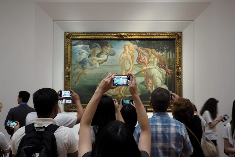 Turistas frente a un cuadro haciéndole fotos con el móvil.
