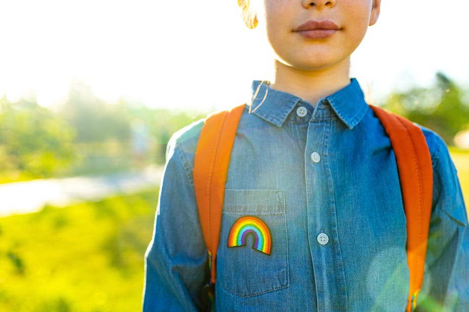 Child wearing backpack and rainbow pin