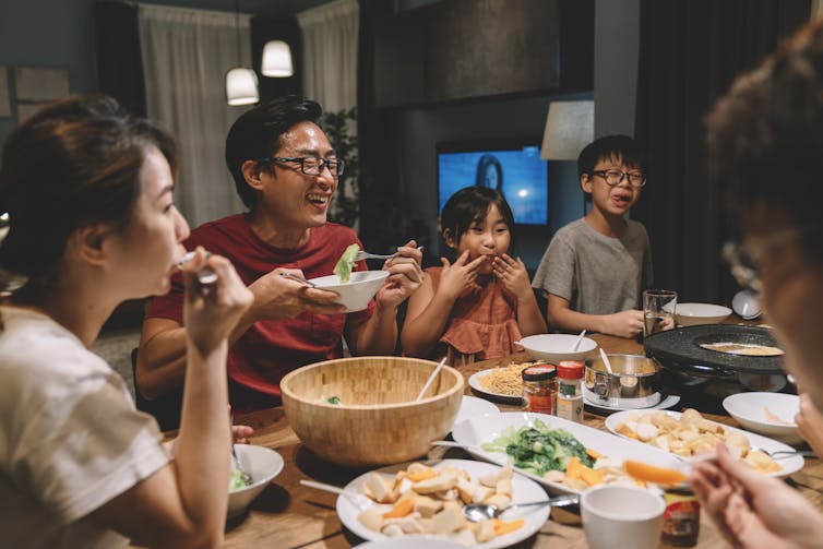 Family smiling and eating together around a dinner table