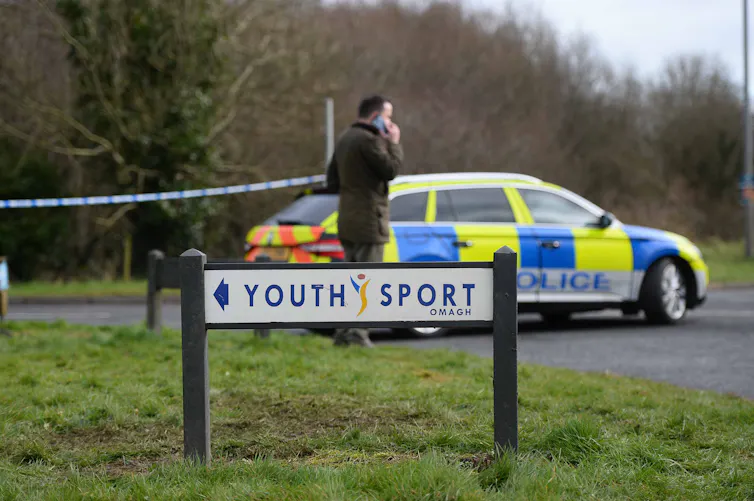 A sign reading 'youth sport' in front of a police car and cordon tape.