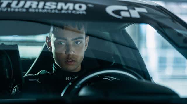 Archie Madekwe sat in a Gran Turismo car.