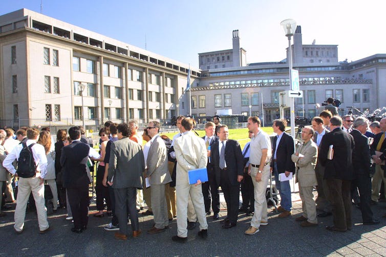 Many people lined up outside some large buildings.