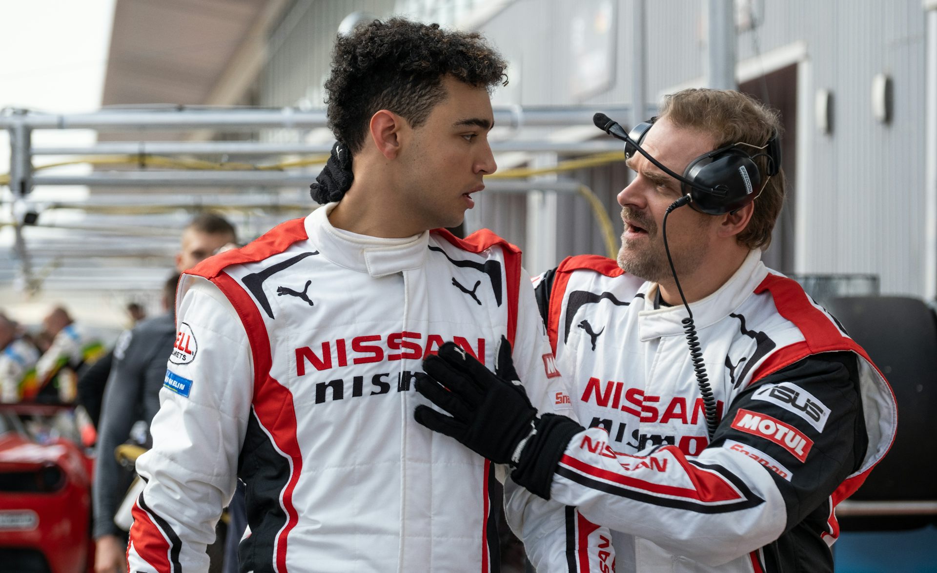 Archie Madekwe and David Harbour wearing white and red racing leathers.