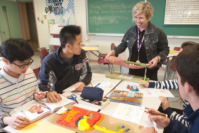 a teacher brings manipulables to a table of high school students