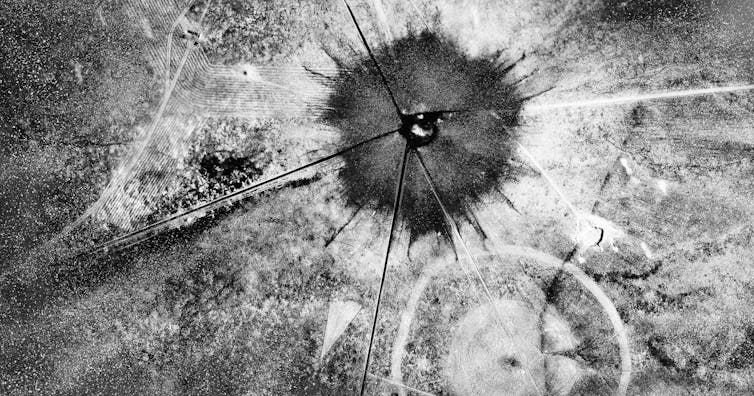 An aerial photo showing a large dark center with disbursing particles in the distance.