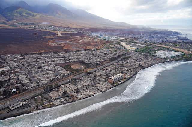 An aerial image shows damaged and destroyed homes and businesses along a coast line