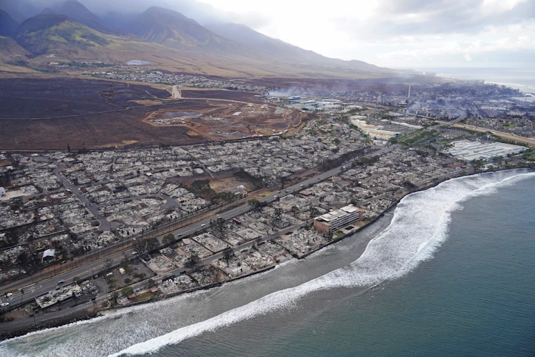 An aerial image shows damaged and destroyed homes and businesses along a coast line
