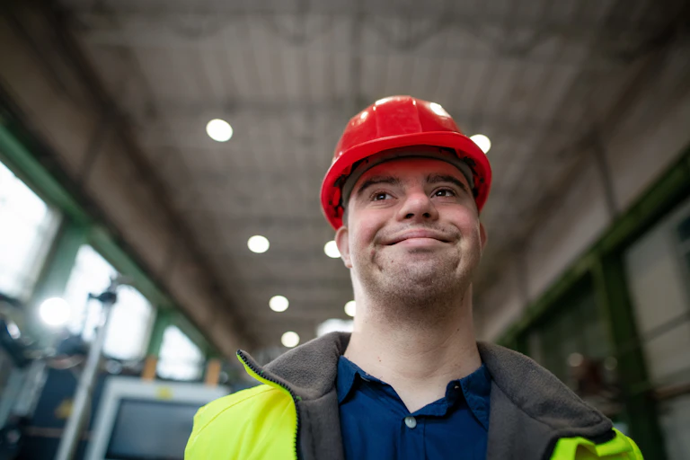 young man with hard hat walks through warehouse