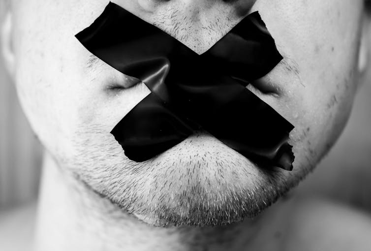 Close-up of a man's mouth covered by black tape.