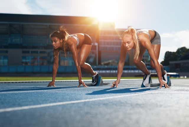 Two female athletes at starting position ready to start a race 