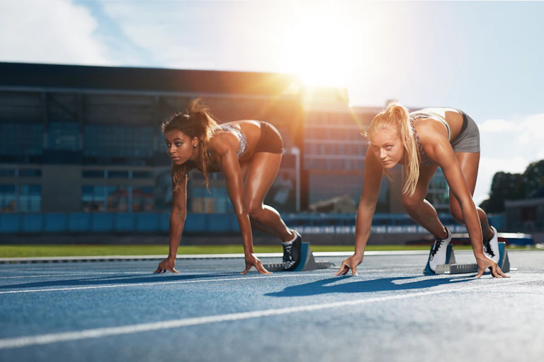 Two female athletes at starting position ready to start a race