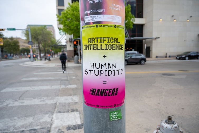 Yellow and pink poster attached to a lamp post that reads 'artificial intelligence plus human stupidity equals bangers.'