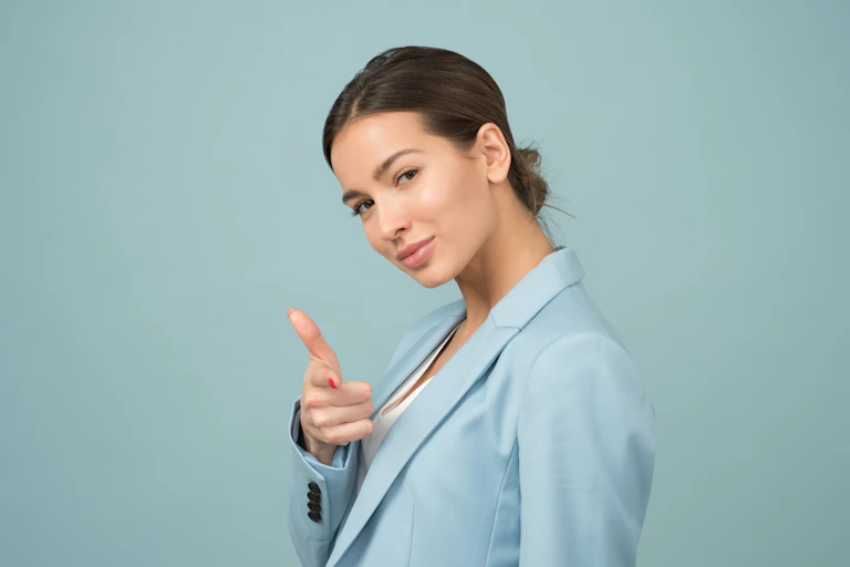 A woman in a light blue blazer giving a thumbs up sign