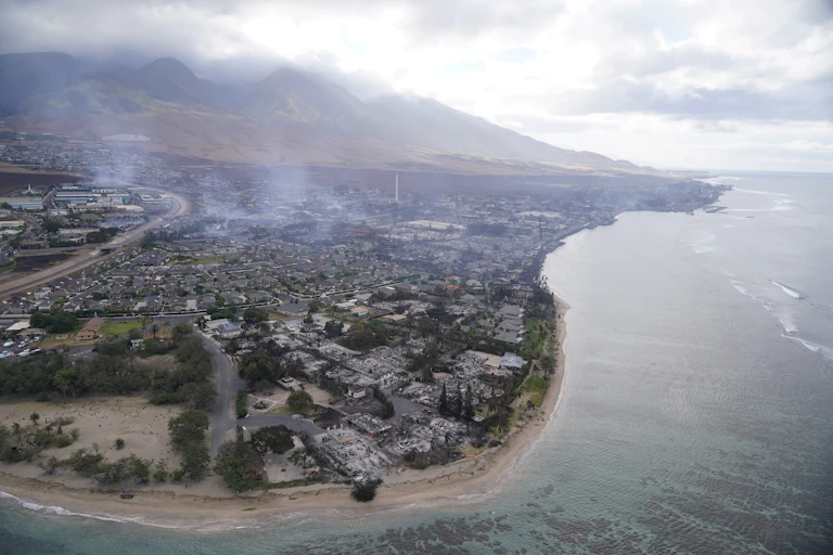 Una vista aérea que muestra el humo que se eleva alrededor de las montañas y las casas quemadas.