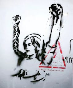 Iranian street art shows a woman raising her arms, with fists clenched.