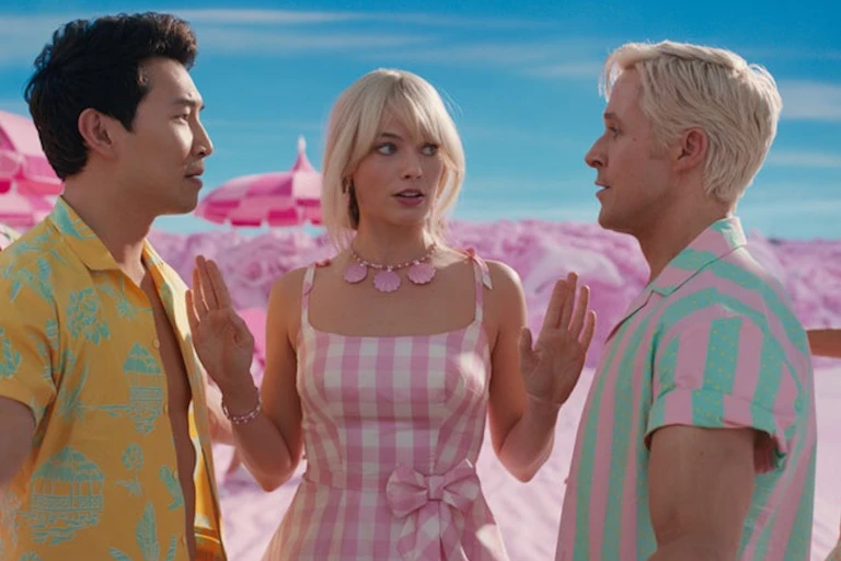 Barbie, dressed in pink holds up her hands, on her right is Ken 1 and on her left is Ken 2.