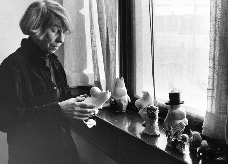 An older woman looking at some children's toys called Moomins which she created.