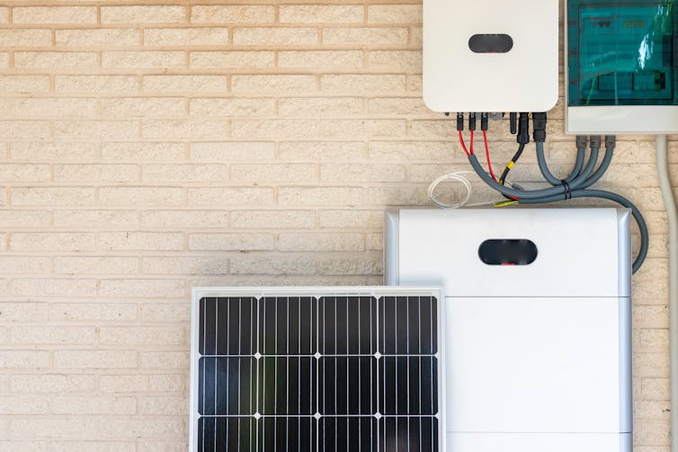 Solar panel ready to be installed in front of a household battery mounted on a wall