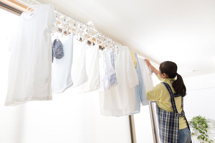 A woman hangs up washing in an indoor setting.