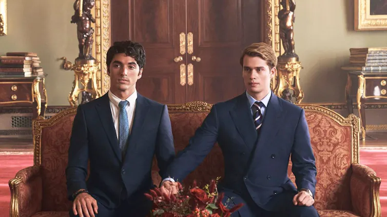 Alex and Henry in suits, holding hands.