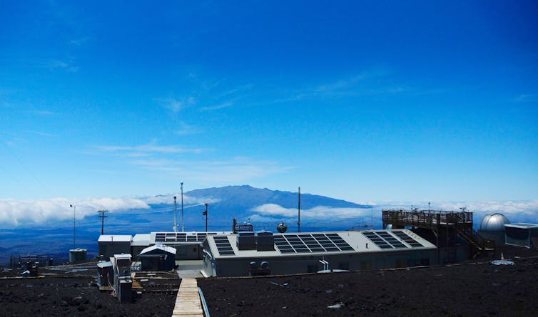 Un centro de investigación con nubes y una montaña en la distancia.