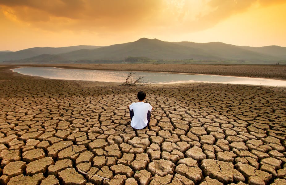 A child sat on a drying lake.