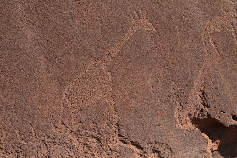 Image of a giraffe carved in red rock.