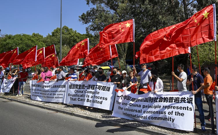 Protesters hold Chinese flags and banners supporting One China policy