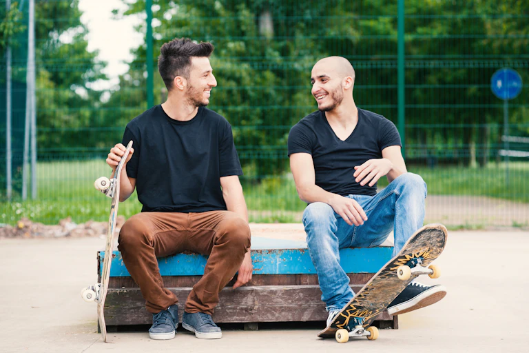 Two men with skateboards sit talking