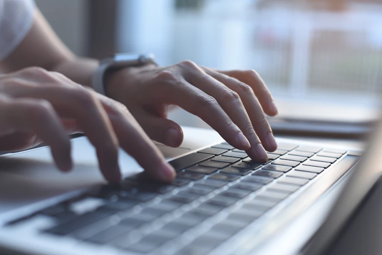 Woman typing on laptop keyboard.