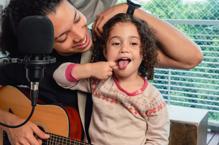 Toddler distracts their parent from recording music.
