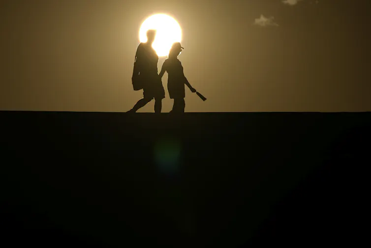two people silhouetted by the sun