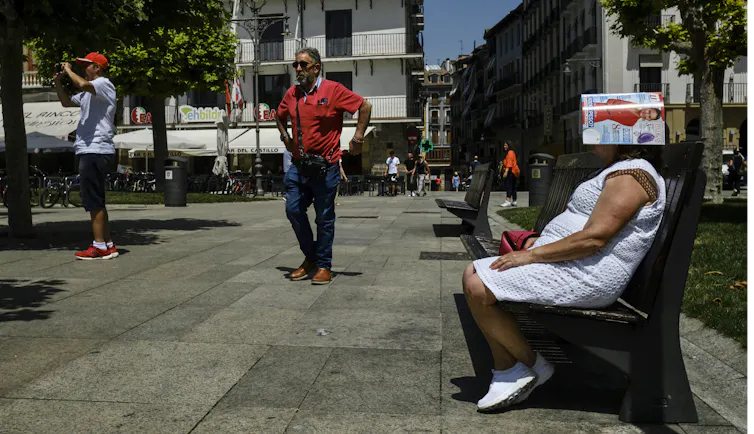 women sits with magazine on head as others walk past