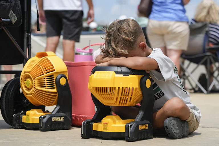 young boy hugs cooling fan