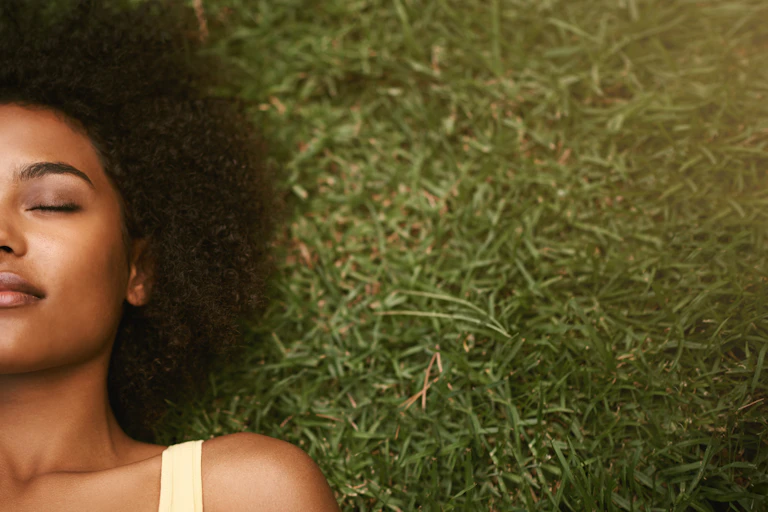 woman lies on grass with eyes closed