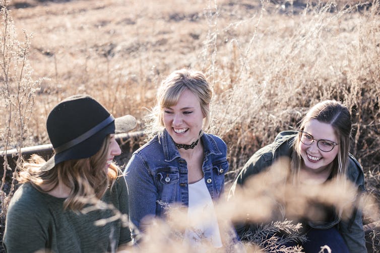 friends sit and laugh outdoors