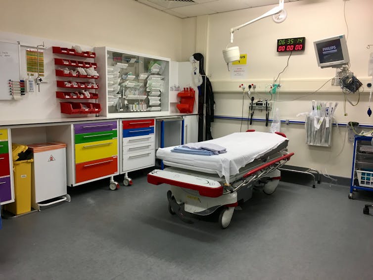 An empty bed in a hospital surrounded with medical equipment
