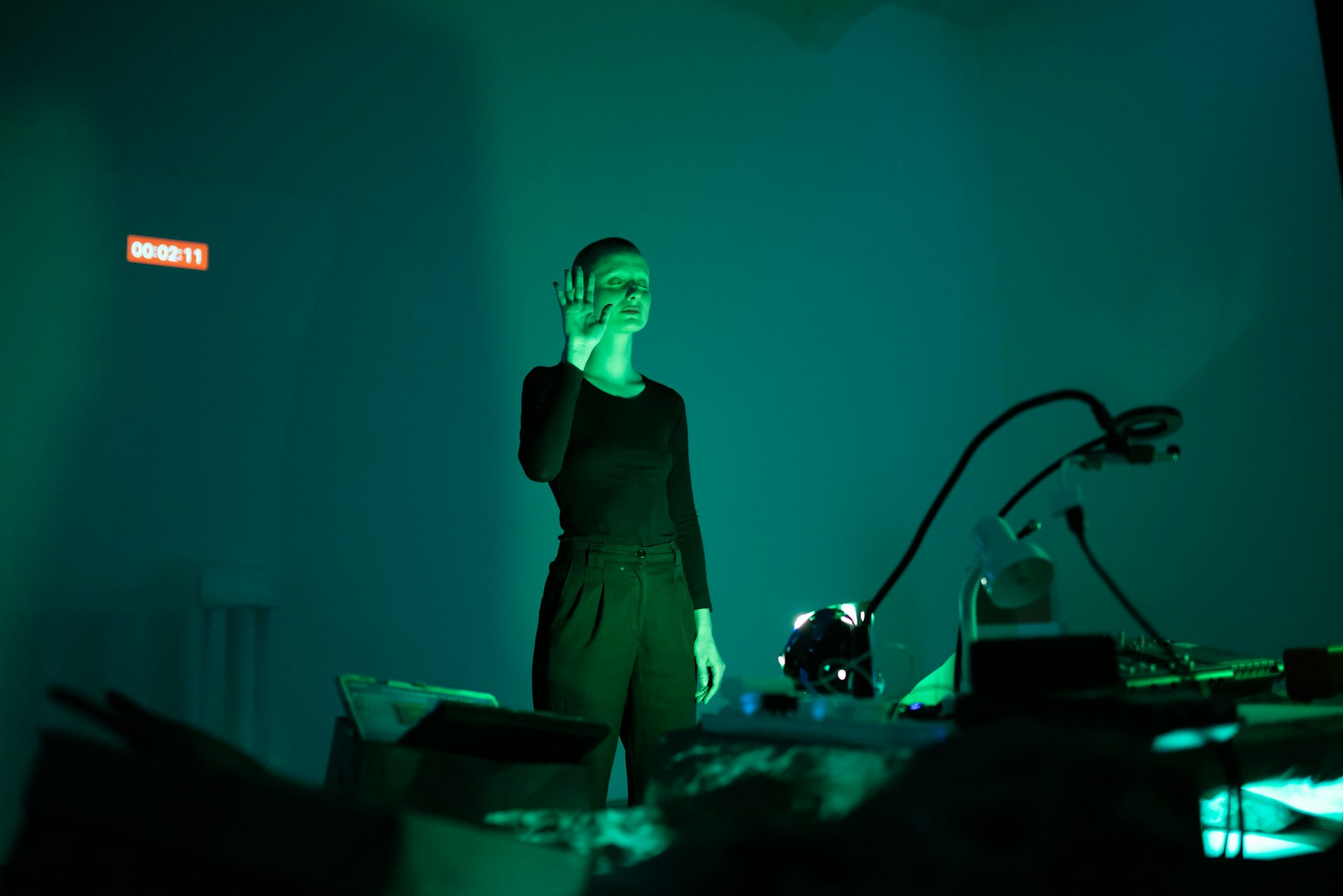 A woman standing on stage bathed in green light.