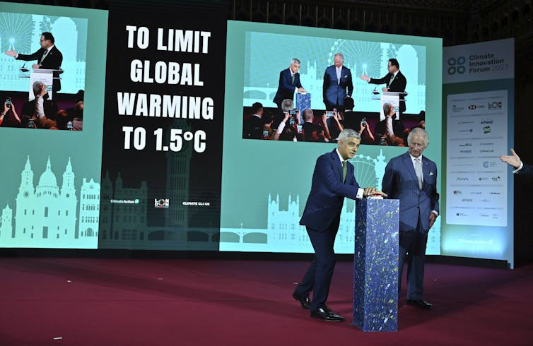 London Mayor Sadiq Khan and King Charles III stand at a podium on stage.