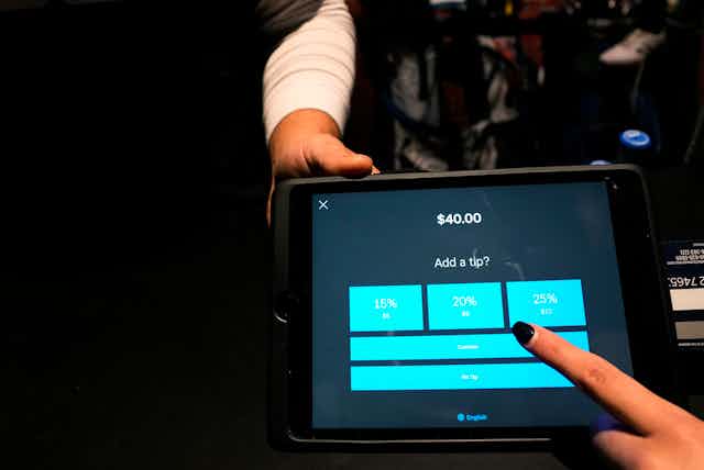 A tipping menu with pre-set options ranging from 15-25% is displayed on a card reader tablet.