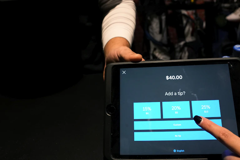 A tipping menu with pre-set options ranging from 15-25% is displayed on a card reader tablet.