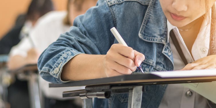 Cropped image of a row of students writing an exam