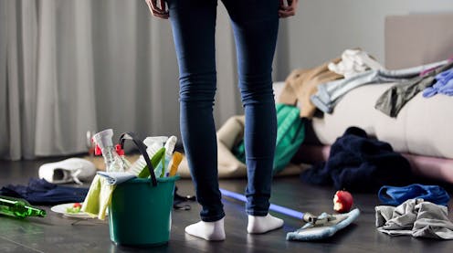 A woman standing in a messy room